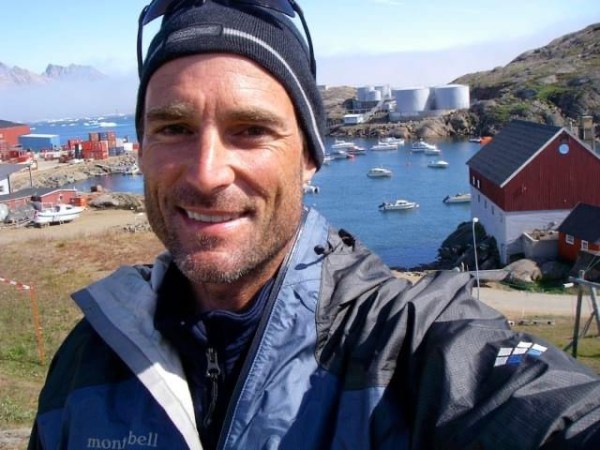My brother David, smiling, with water, boats, and mountains in the background
